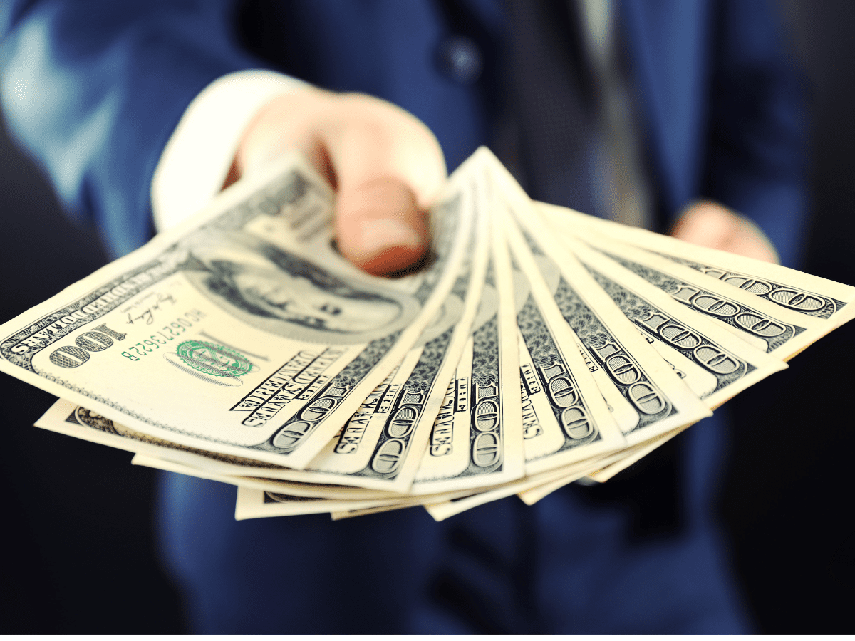 Person handing out a fan of cash.
